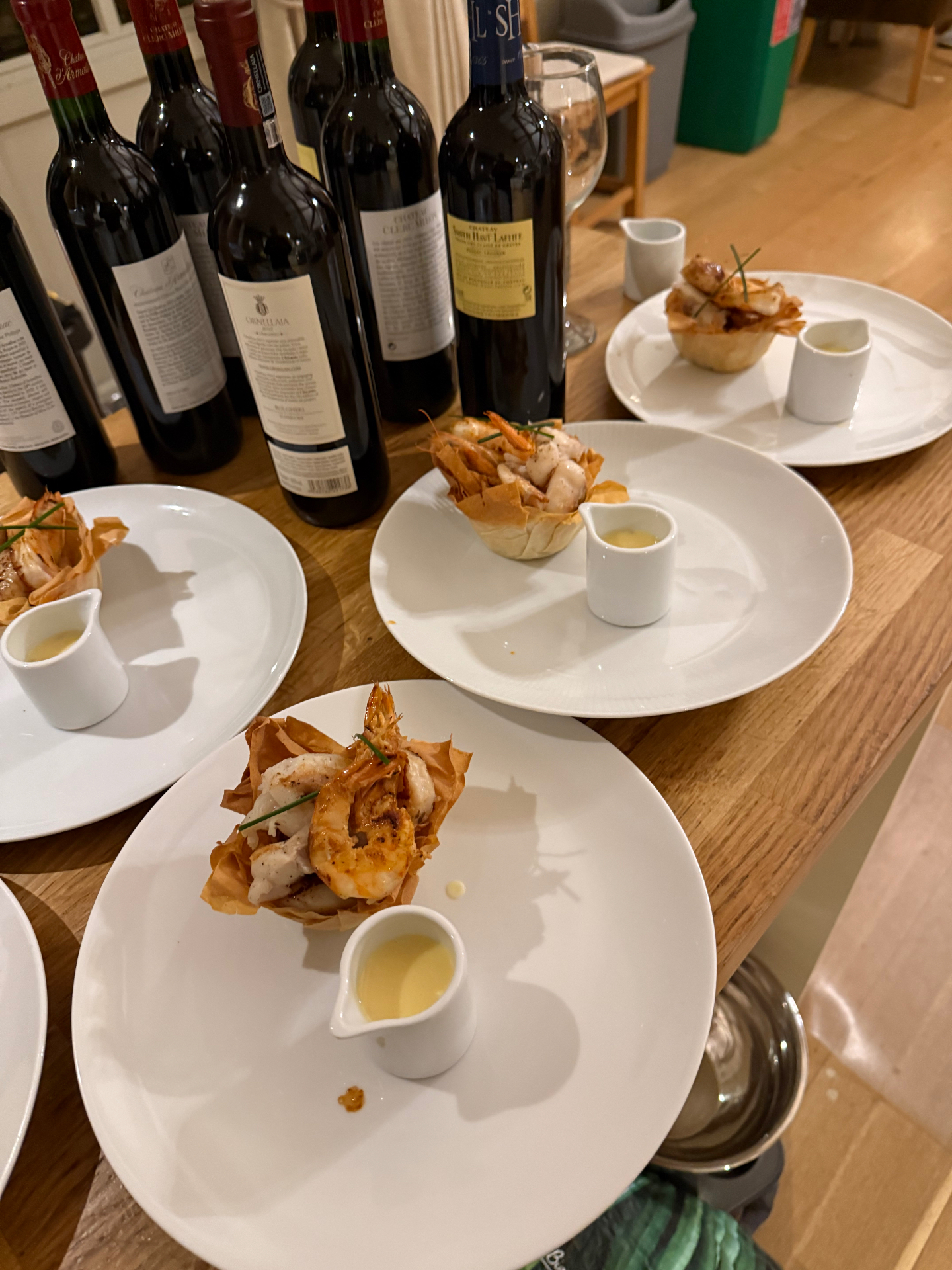 Wine-paired filo pastry seafood baskets served on white plates with a line of red wine bottles — a Lovey Chef private dining tablescape in Bristol