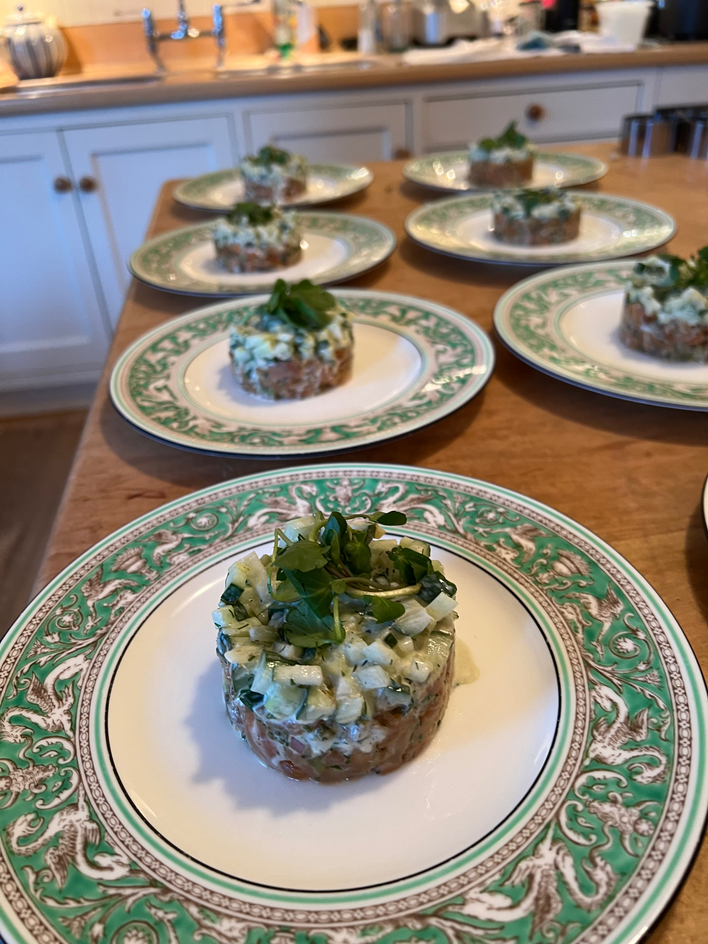 Hand-plated salmon tartare with fresh herbs and cucumber on ornate green-rimmed plates — a Lovey Chef private dining starter prepared in a Bristol home kitchen